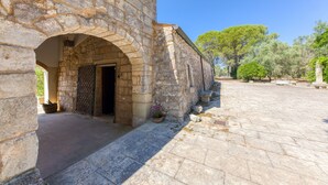 A stone building with an arched doorway, a potted plant, and a paved courtyard.