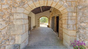 A stone corridor with an archway, a bench, and a potted plant.