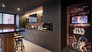 A modern kitchen with a bar area, Star Wars arcade machine, and a brick accent wall. - Modern and Cozy 1D1B Santiago Downtown Near Movistar Arena (Santiago)