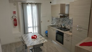 A compact kitchen with a dining table, a gas stove, and a built-in oven. - Messina Apartments (Messina)
