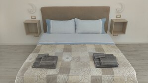 A bed with a patterned bedspread, two pillows, and folded towels on the bed. - Messina Apartments (Messina)