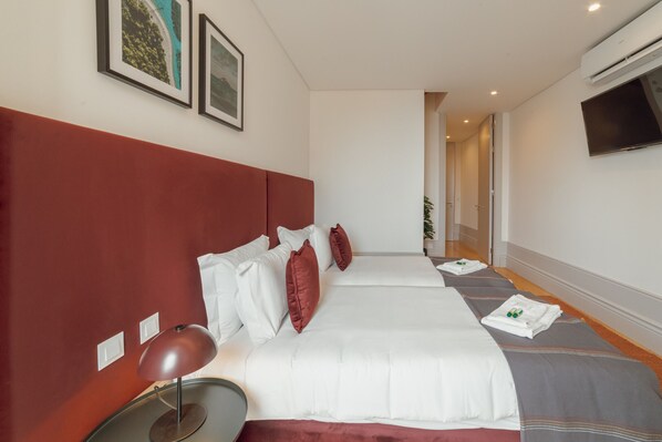 Une chambre d’hôtel avec un grand lit, une table de chevet, une lampe et un téléviseur fixé au mur.