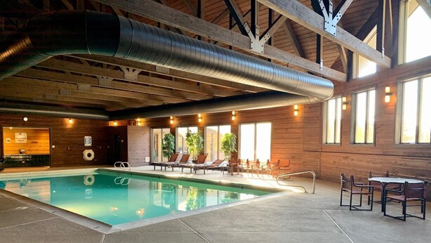 An indoor swimming pool with lounge chairs and tables, wooden beams, and large windows. - Fabulous one bedroom condo less than 5 min from Purgatory with ski shuttle stop (Durango)