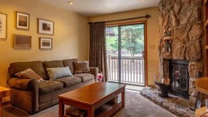 A living room with a stone fireplace, a sofa, and a coffee table. - Fabulous one bedroom condo less than 5 min from Purgatory with ski shuttle stop (Durango)