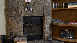A stone fireplace with a welcome sign, a bookshelf with books and decorative items, and a round coffee table with a remote control. - Fabulous one bedroom condo less than 5 min from Purgatory with ski shuttle stop (Durango)
