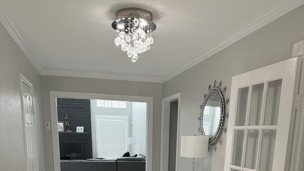 A hallway with a chandelier, a white console table, a mirror, and a door with glass panels. - Houston’s poolside vacation home (Houston)