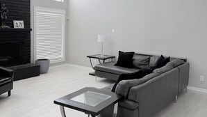 A modern living room with a fireplace, a sofa, a coffee table, and a side table. - Houston’s poolside vacation home (Houston)