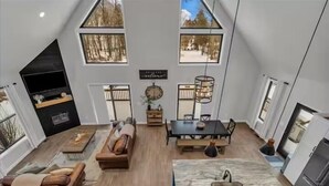 A modern loft-style living space with a kitchen, dining area, and seating area. - Lake House With Beach Access, Theater, Hot Tub (Port Austin)