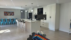 Une cuisine moderne avec des meubles blancs, un îlot central et un coin repas avec des chaises bleues.