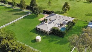 Une grande maison de plain-pied, dotée d’un toit en pente, entourée d’une pelouse bien entretenue et d’une clôture blanche.