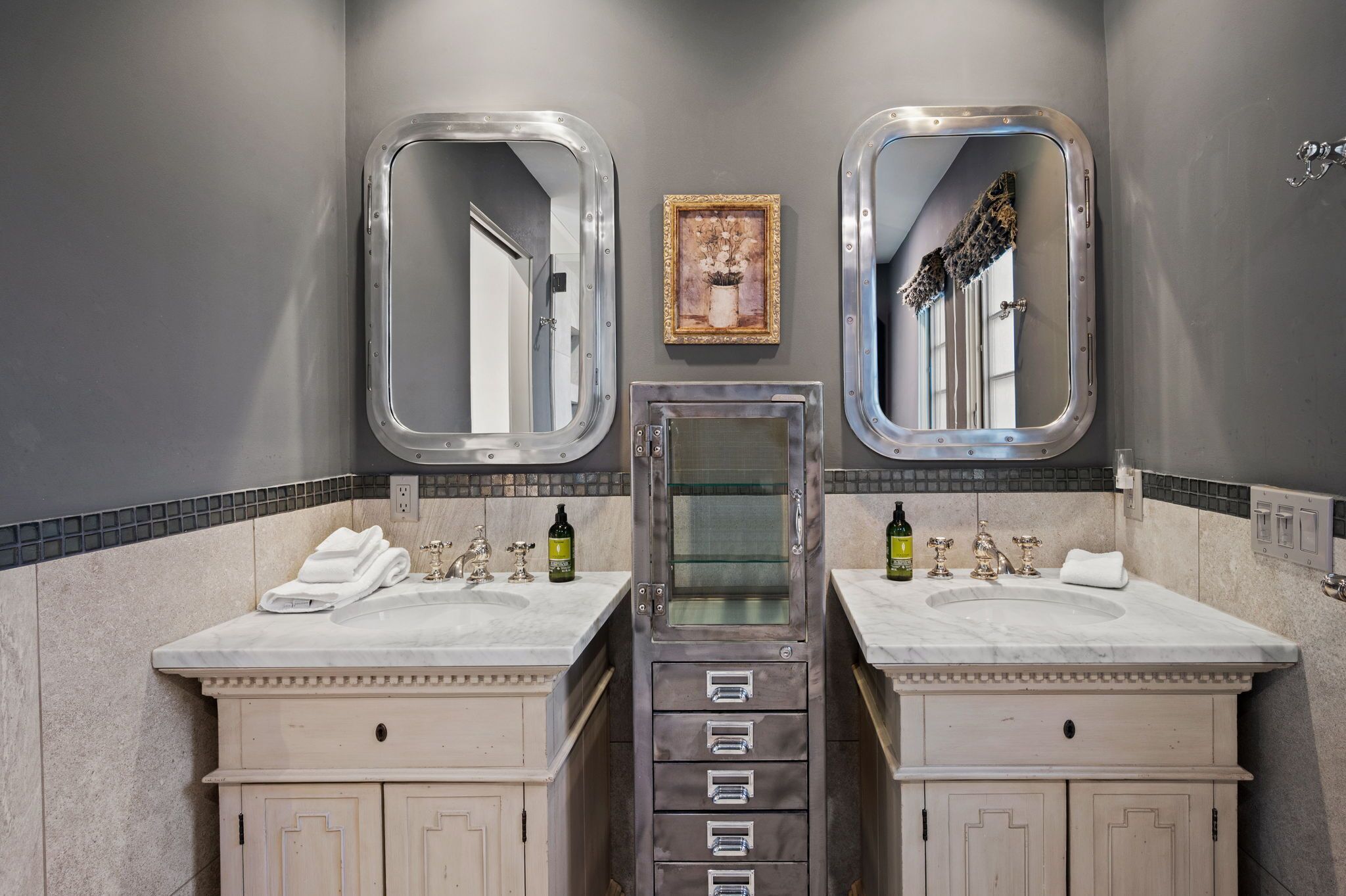 A bathroom with two sinks, a mirror, and a framed picture on the wall.