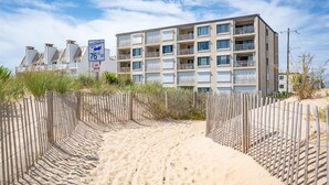 A beachfront hotel with a modern design, featuring multiple balconies and a sandy beach area.