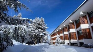 A snow-covered building with multiple balconies and a clear blue sky. - Hotel El-Arz (Boghni)