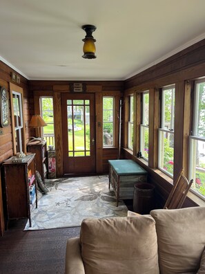 Une pièce aux murs en bois, avec un banc, une table et une porte donnant sur l’extérieur.