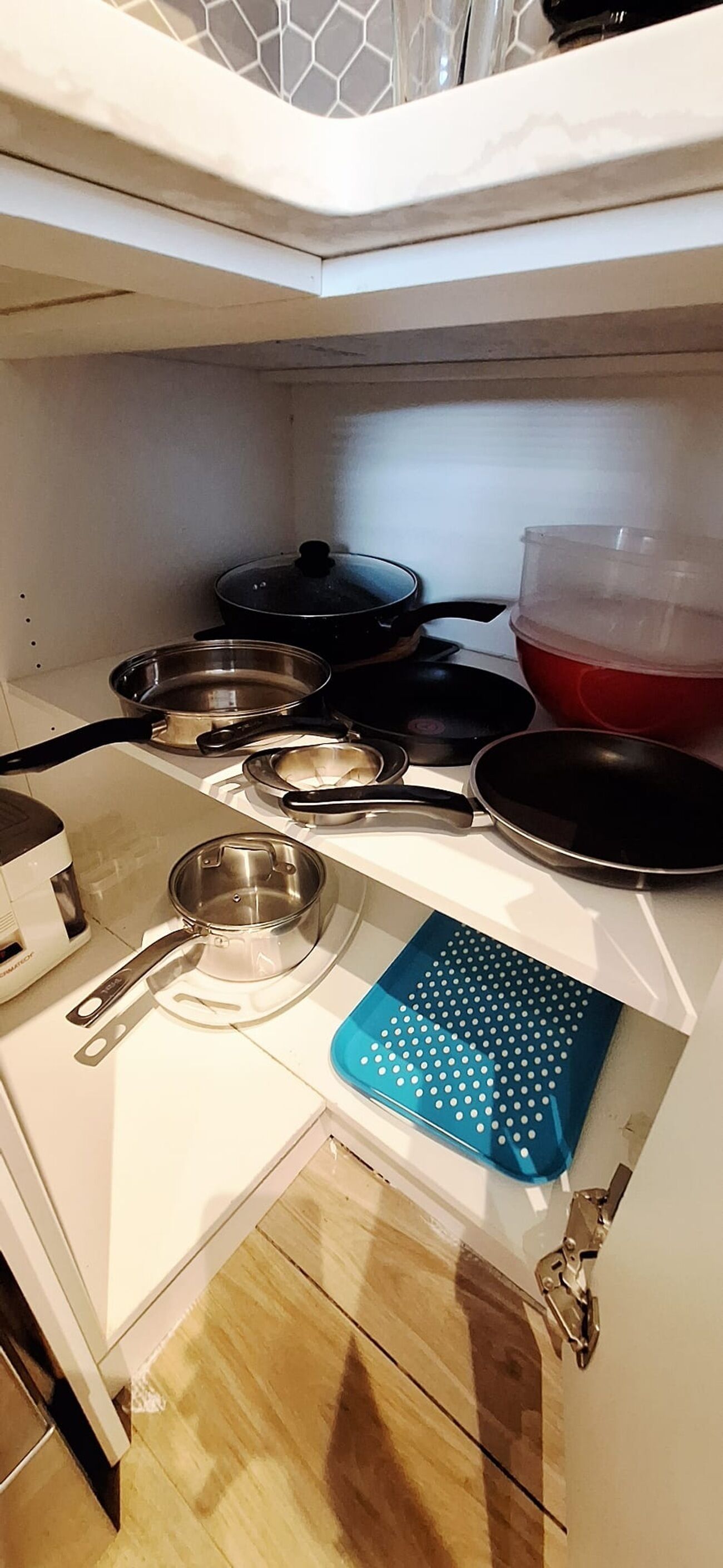 A kitchen with a white countertop, a blue cutting board, and various pots and pans.
