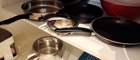 A kitchen with a white countertop, a blue cutting board, and various pots and pans.