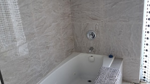 Ein Badezimmer mit Badewanne, Duschbereich und gefliestem Boden.