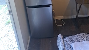 Eine kleine Küche mit Kühlschrank, Mikrowelle und einem Tisch mit einem gelben Behälter.