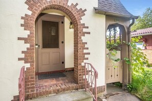 Une entrée de maison avec une porte marron, un arc en briques et un petit porche.