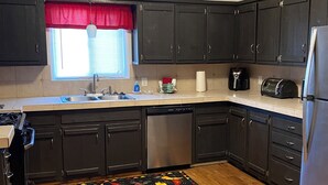 Una cocina moderna con armarios oscuros, electrodomésticos de acero inoxidable y suelo de madera.
