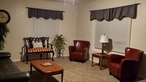 Una sala de estar con un sofá, sillones, una mesa de centro, un reloj y una lámpara.