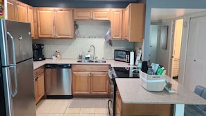 A modern kitchen with wooden cabinets, stainless steel appliances, a dishwasher, a sink, and a microwave.