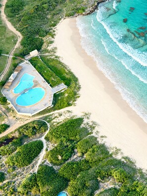 An aerial view of a beach resort with a swimming pool, a beach, and surrounding greenery. - Waterfront. A stylish and relaxing suite in Mont Vernon, Orient Bay. Pool. Beach. View. (Saint-Martin)