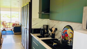 Une cuisine moderne avec des meubles de couleur verte, un lave-linge encastré et un coin repas offrant une vue agréable.