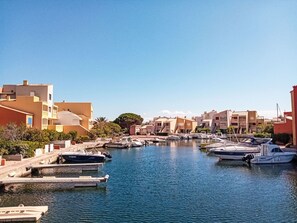 A marina with boats docked, surrounded by buildings with balconies and a clear sky. - Dominica by Interhome (Le Barcarès)