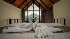 Ein Schlafzimmer mit Bett, einer herzförmig arrangierten Handtuchgarnitur und Bergblick durch ein Fenster.