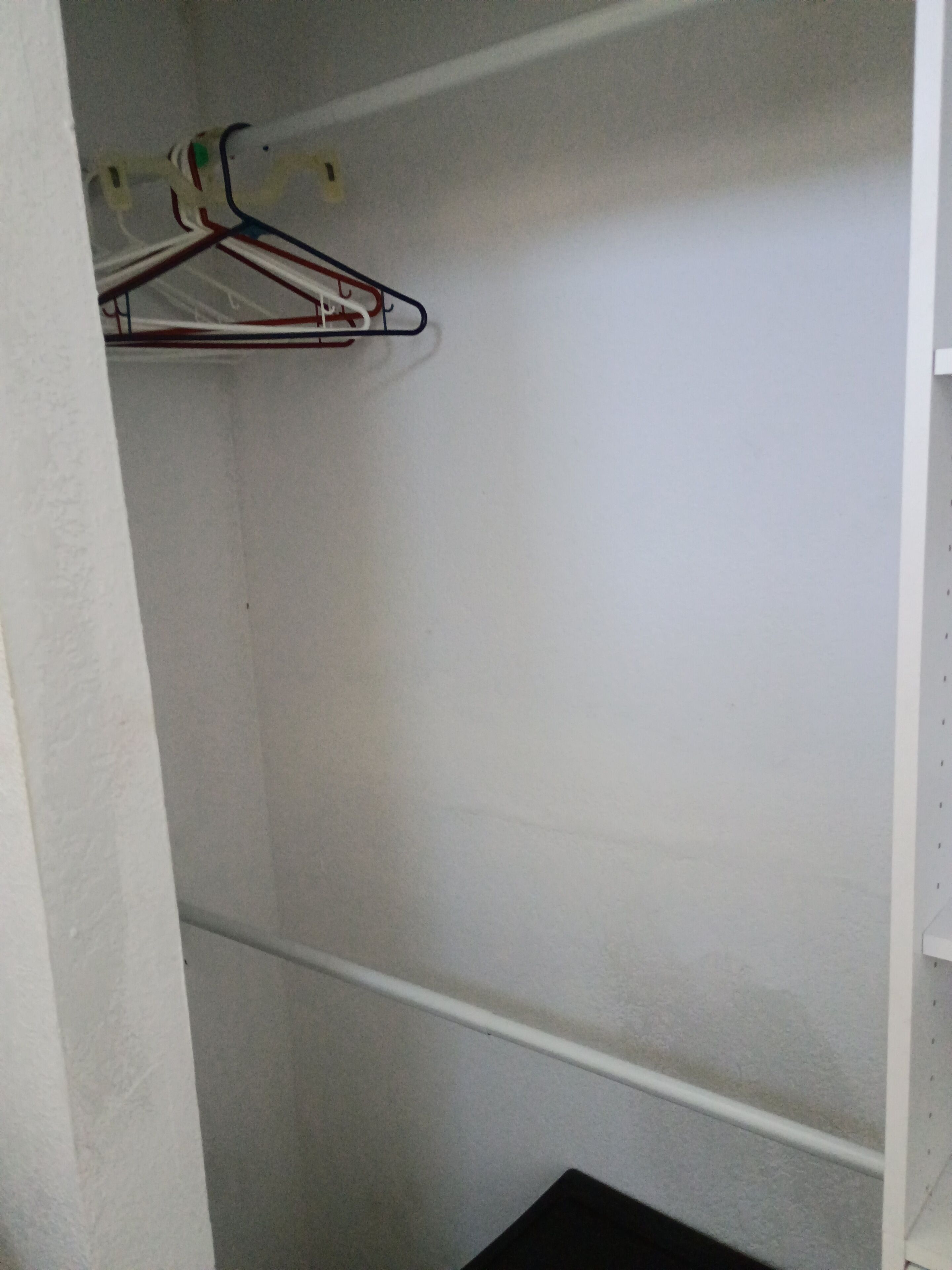 Een kast met kledingroede en plank.