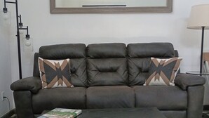 A living room with a sofa, a coffee table, a lamp, and a wall-mounted mirror.