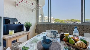 Ein Essbereich mit einem Tisch, der für das Frühstück gedeckt ist, einschließlich Früchten, einer Kerze und Blick auf die Skyline durch das Fenster.