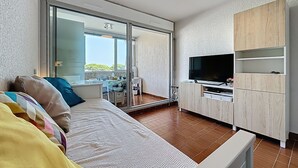 Ein modernes Schlafzimmer mit Bett, Fernseher und einem Balkon mit Tisch und Stühlen.