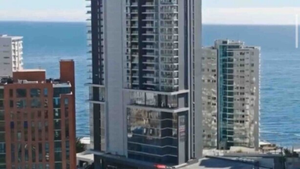 A high-rise building with multiple balconies, situated near a body of water. - Apartamento Reñaca Live (Viña del Mar)