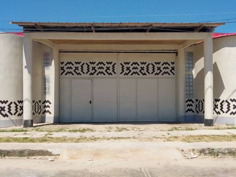A building with a large garage door, patterned walls, and a concrete ground.
