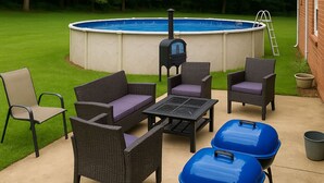 Patio con piscina, mobiliario exterior y una parrilla.