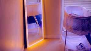 Una habitación con una cuna, un letrero de neón y un espejo.