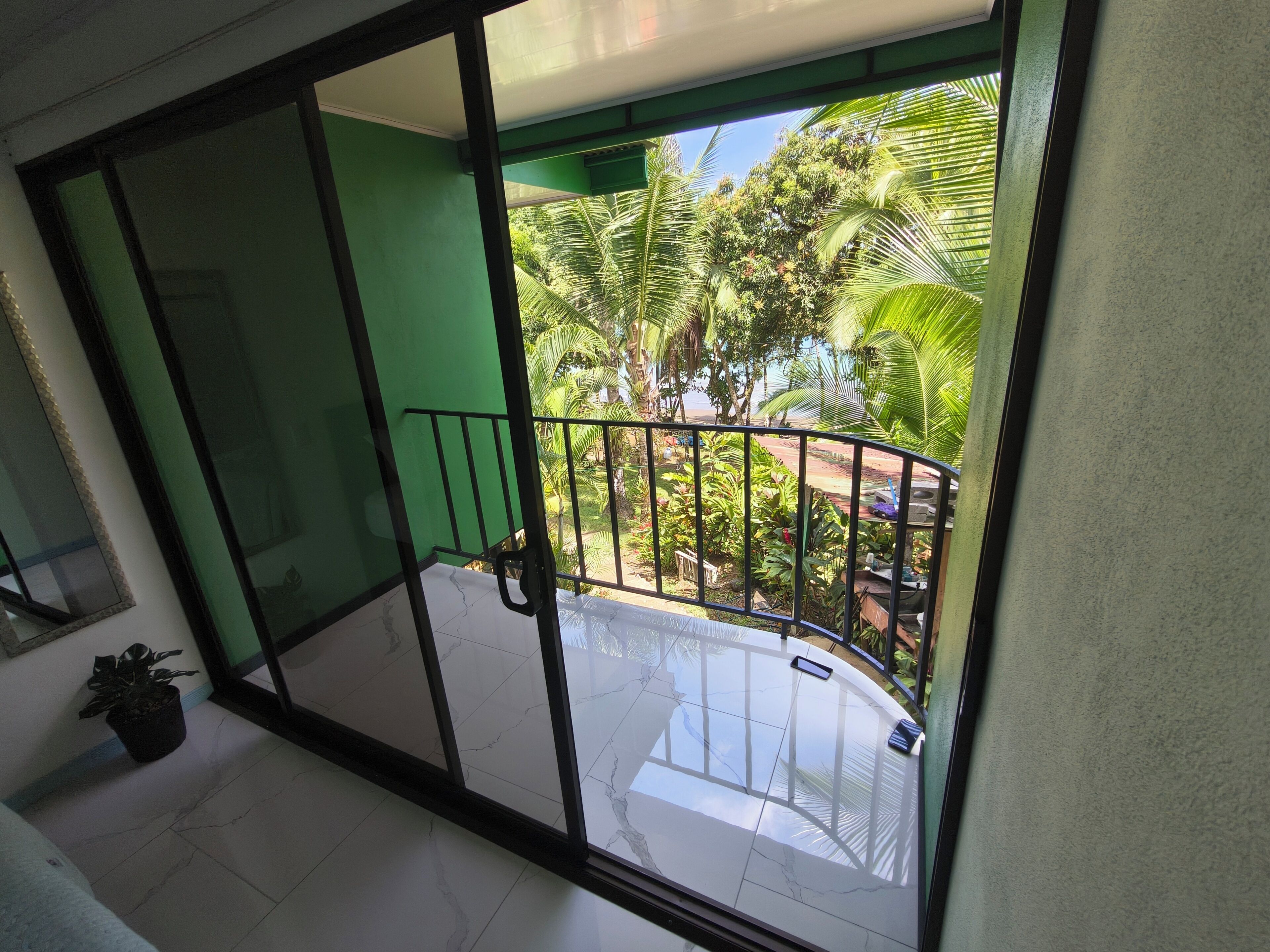 Un balcon donnant sur un jardin et une voiture.