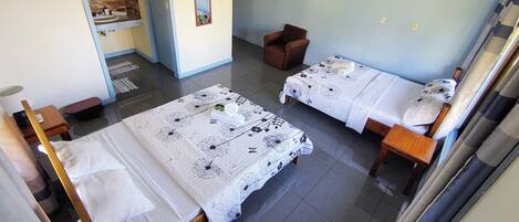 A hotel room with two beds, a bathroom, and a small seating area.