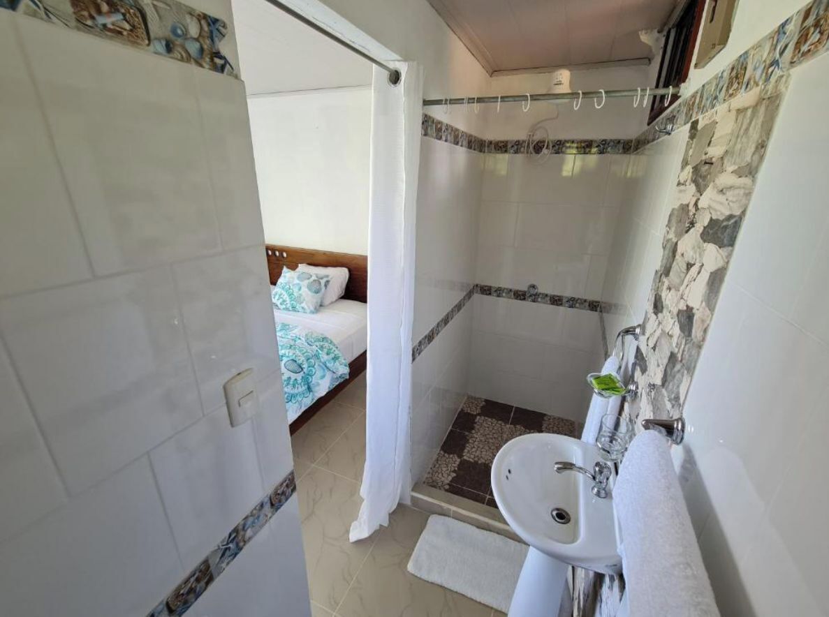 Ein Badezimmer mit Dusche, Waschbecken und einem Bett mit blauer und weißer Bettdecke.
