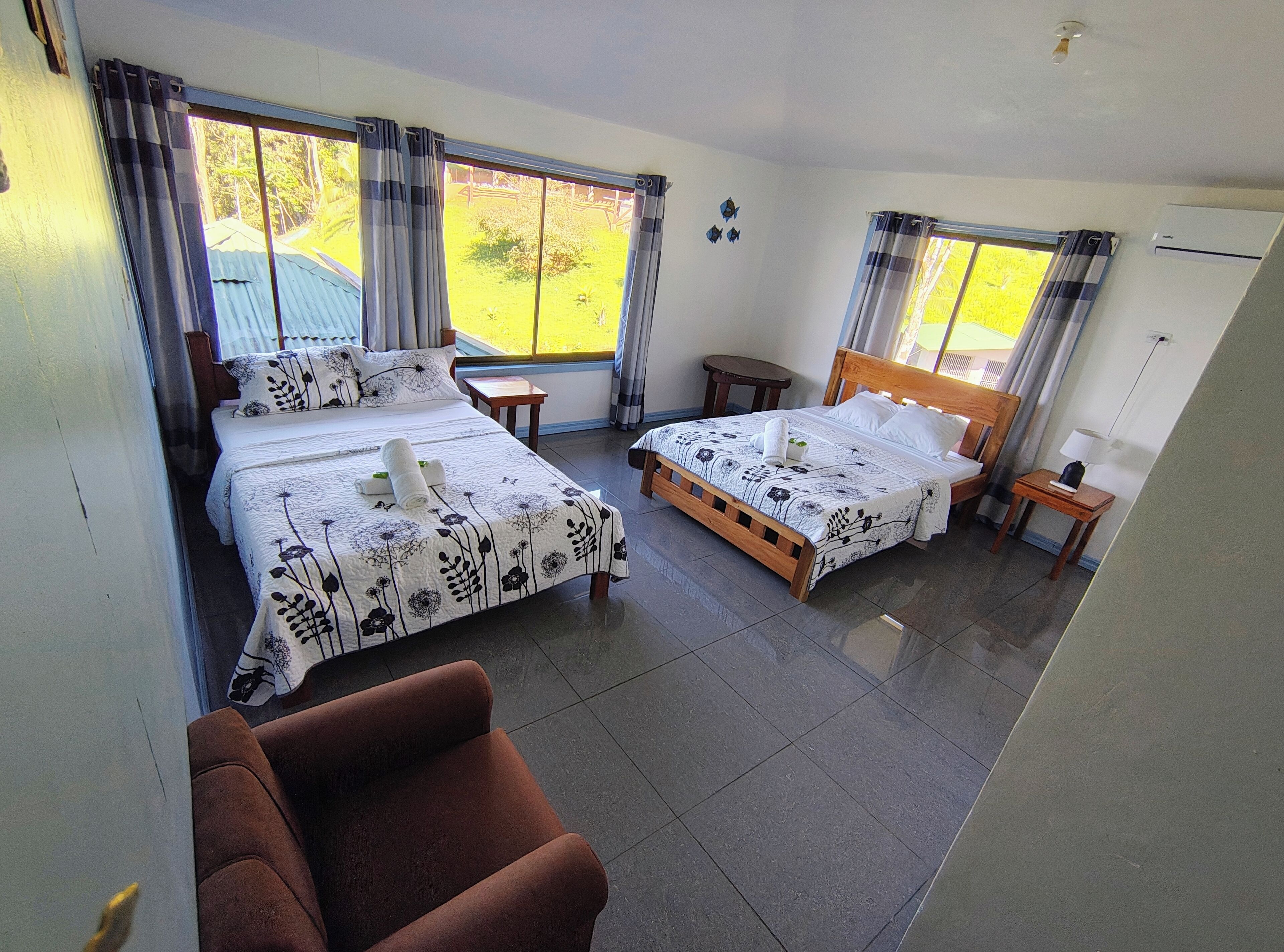 A hotel room with two beds, a sofa, and a view of the garden.
