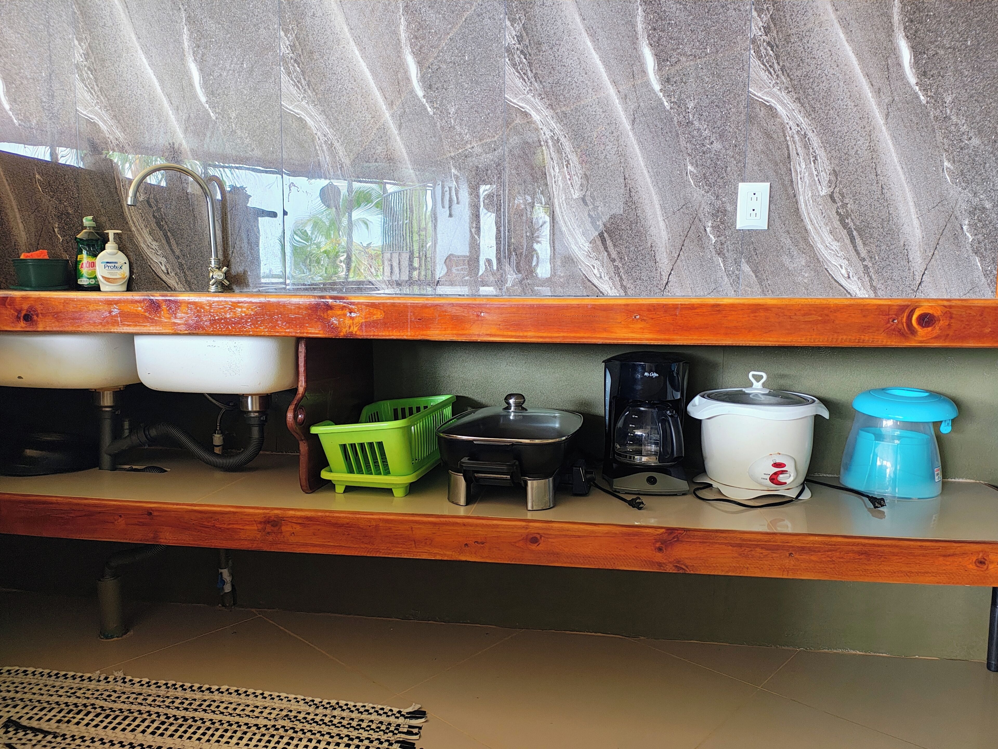 A kitchen with a sink, countertop, and various appliances including a coffee maker and a slow cooker.
