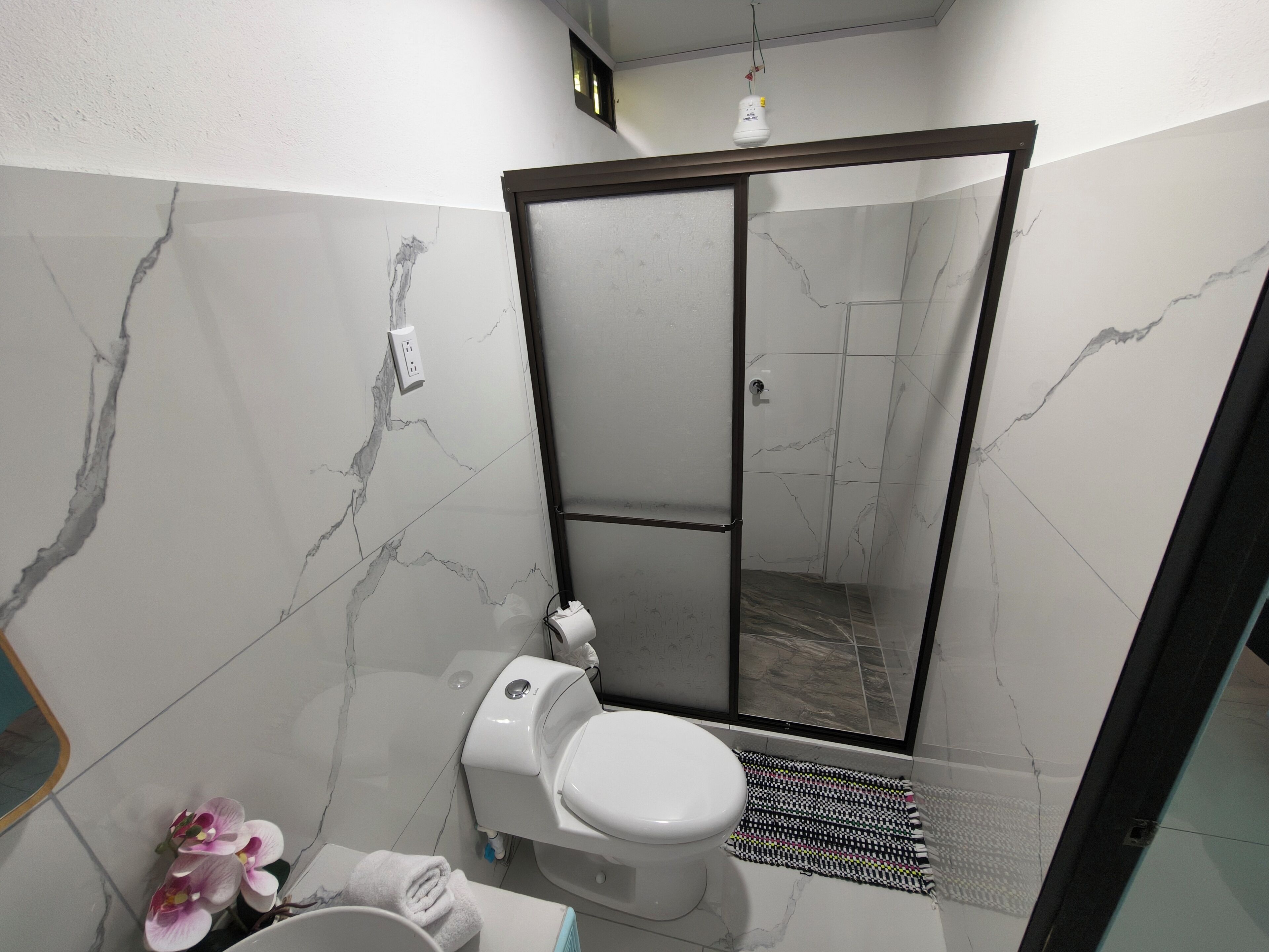 A bathroom with a toilet, a shower, and a sink.