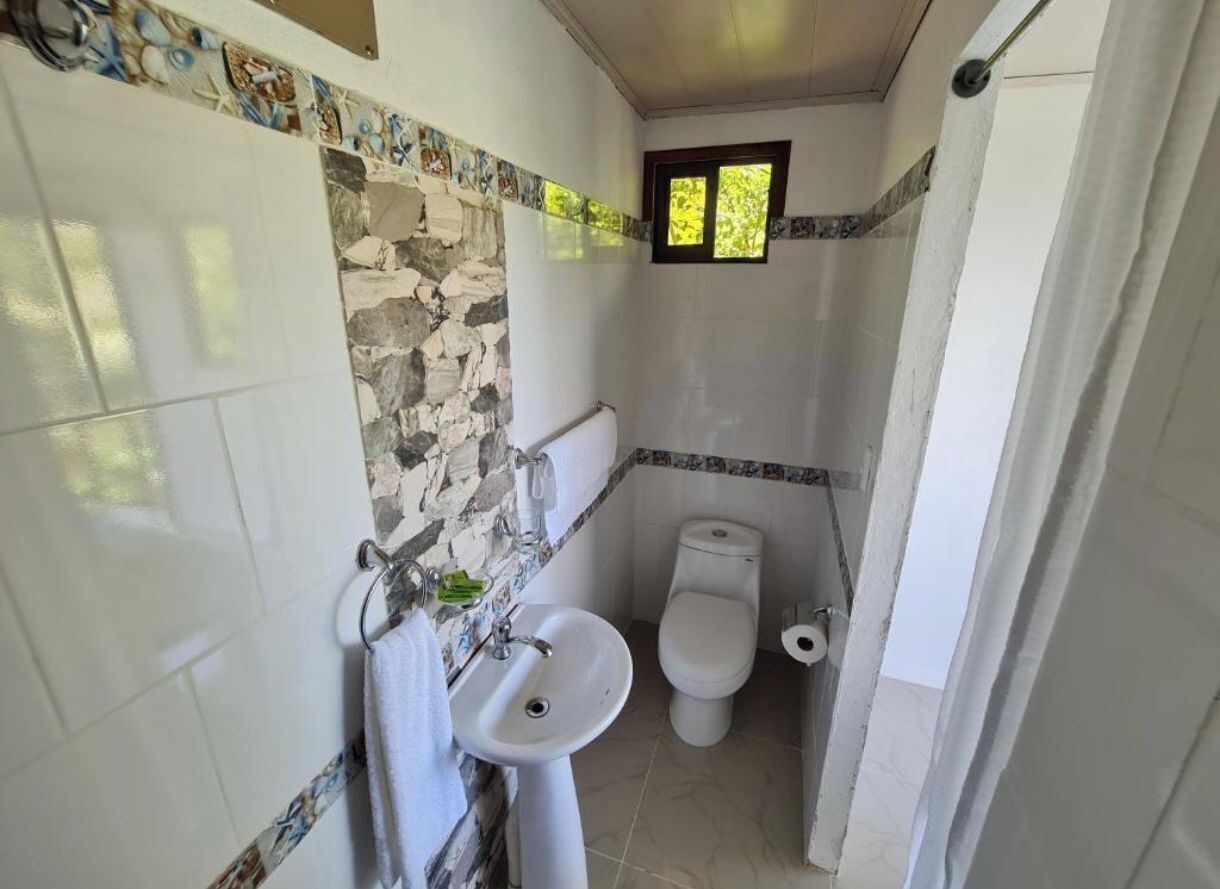 A bathroom with a sink, toilet, and a small window.