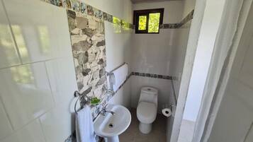 A bathroom with a sink, toilet, and a small window.