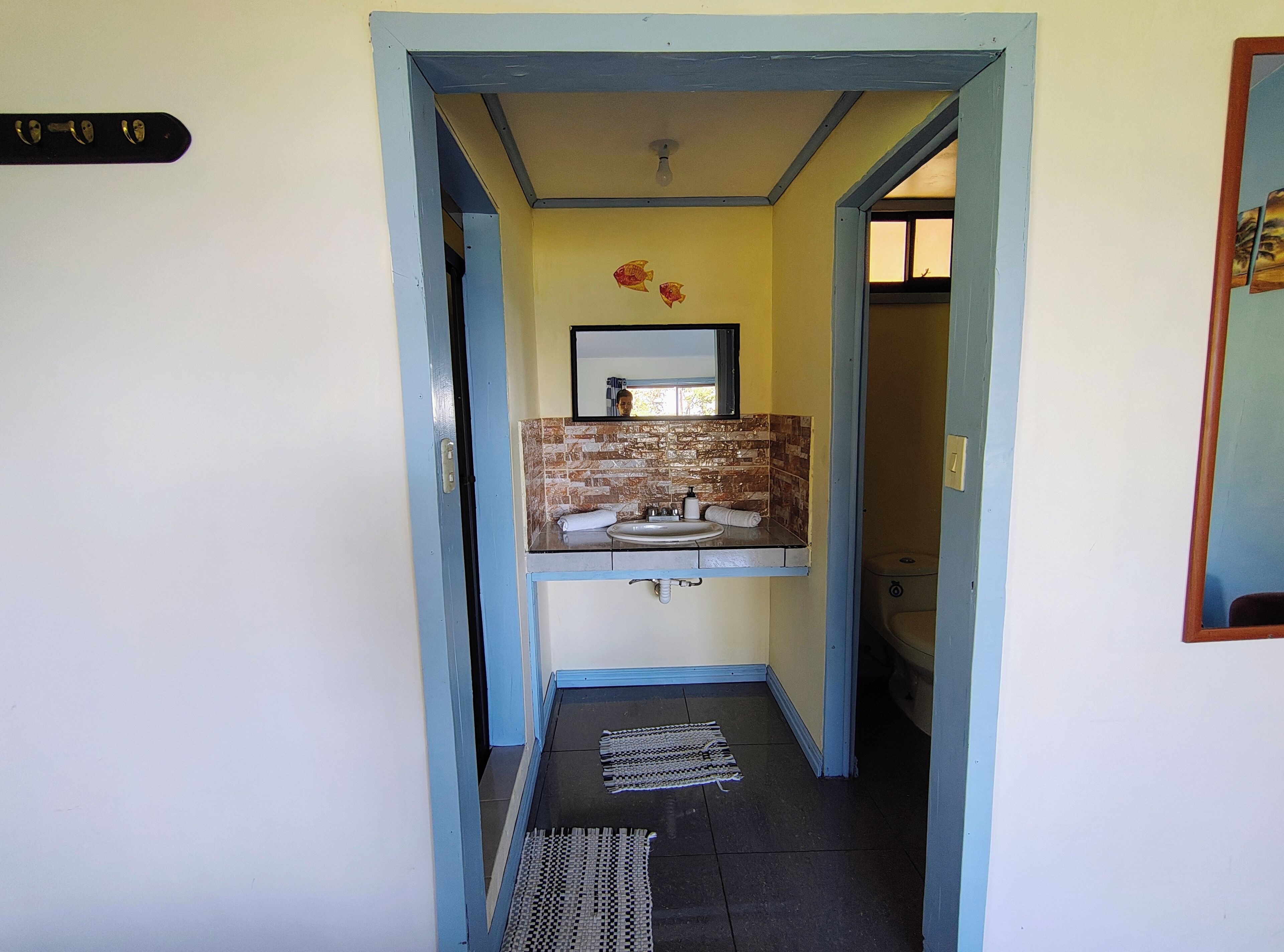 A narrow hallway leading to a bathroom with a sink and mirror.