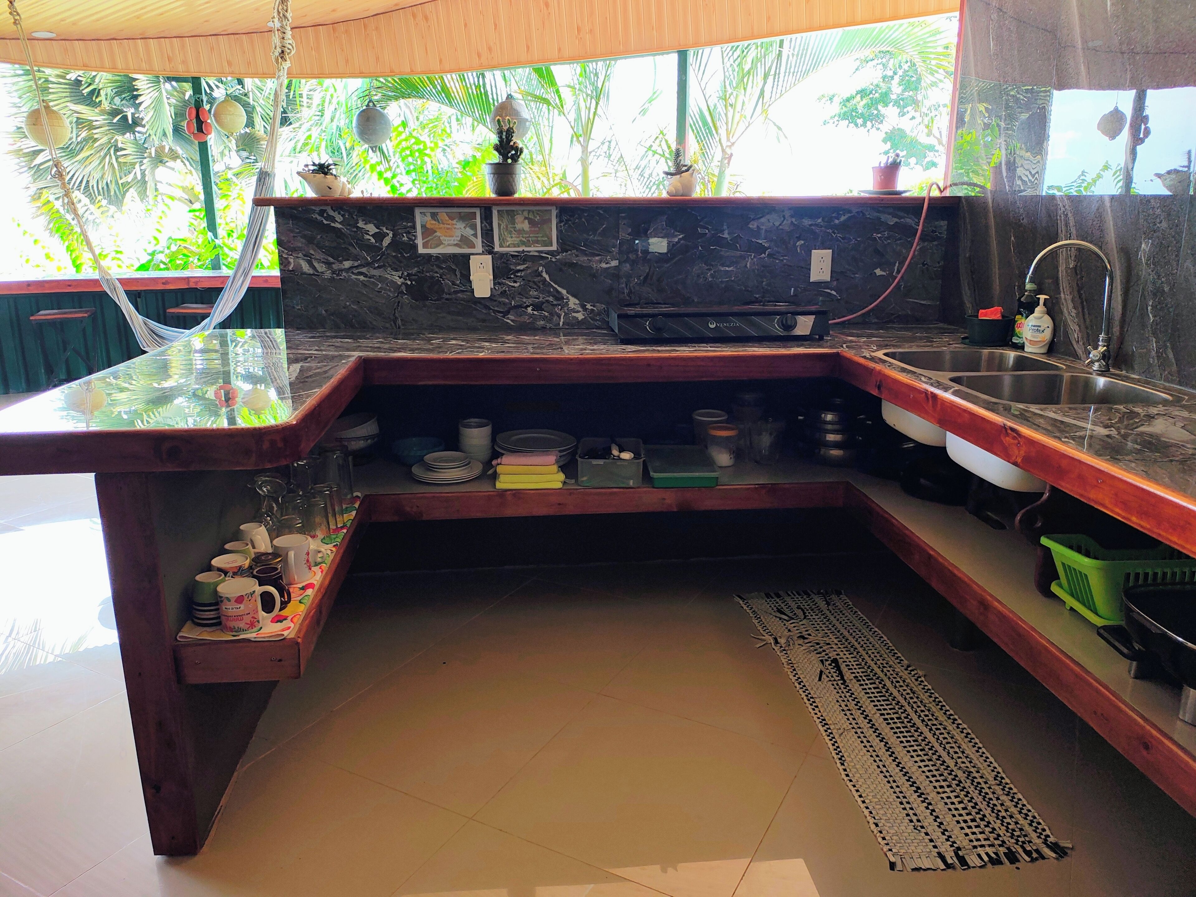 A kitchen with a black marble countertop, wooden shelves, and a sink.