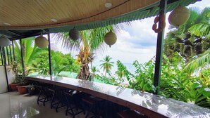 Un long comptoir, propice à la détente et à la contemplation, avec vue sur une plage tropicale et des palmiers.