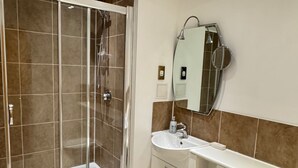 A bathroom with a glass-enclosed shower, a white sink, and a mirror. - 2-bed Apt, Sleeps 7, 5 Mins to Camden Market (London)
